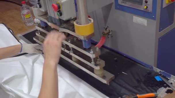 Un hombre trabaja en una máquina de soldadura HDTV con película de PVC. — Vídeo de stock