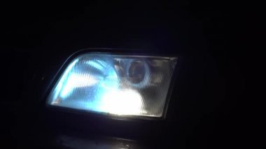 Bir arabanın beyaz farlarını yakın plan çek. Gece ışıklar yanar..