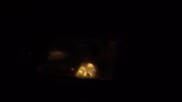 Primer plano de los faros blancos en un coche. luces de marcha se encienden por la noche. — Vídeo de stock