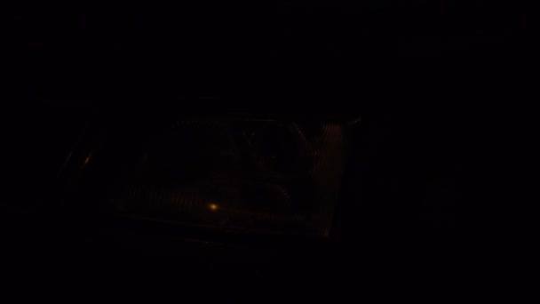 Gros plan des phares blancs sur une voiture. feux de circulation allumés la nuit. — Video