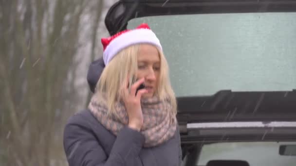 Vrouw in Santa Claus hoed roept op smartphone, kapotte auto. — Stockvideo