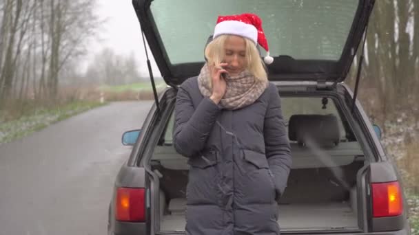 Mujer en Santa Claus sombrero llamadas en el teléfono inteligente, coche roto. — Vídeos de Stock
