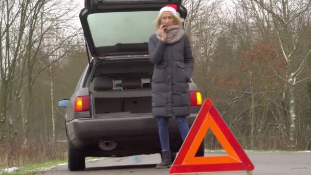 Femme dans le chapeau du Père Noël appelle sur smartphone, voiture cassée. — Video