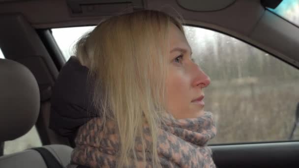 Girl is sad at the wheel of the car, she looks thoughtfully out window — Stock Video