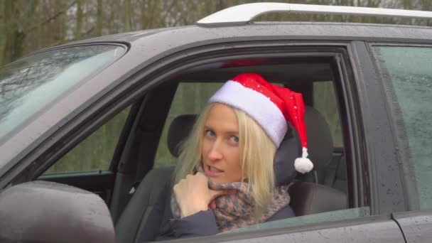 Egy Télapósapkás nő ül a kocsiban, töprengve és szomorúan.. — Stock videók