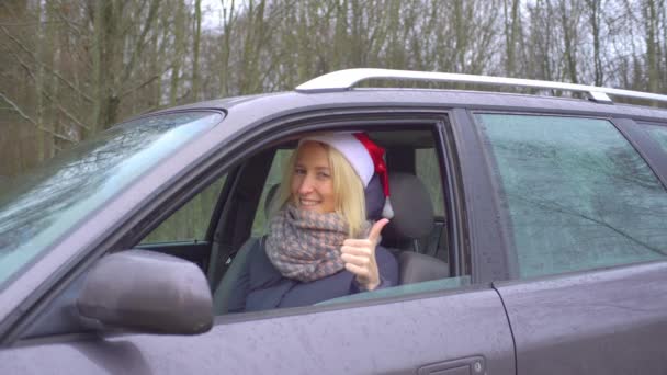 Kvinna i jultomten hatt sitter i bilen, håller upp OK tecken — Stockvideo