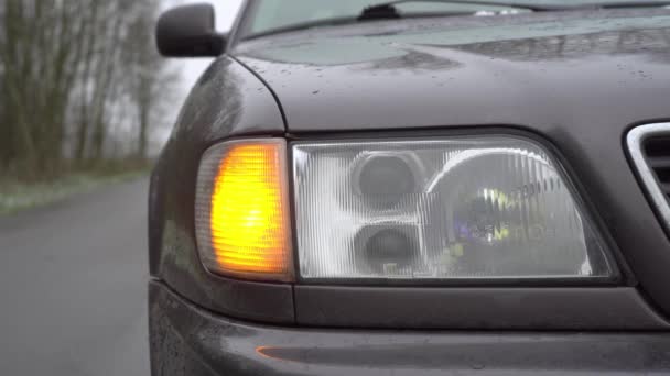 Close-up van het gele voorlicht rechts knipperend op de auto. — Stockvideo