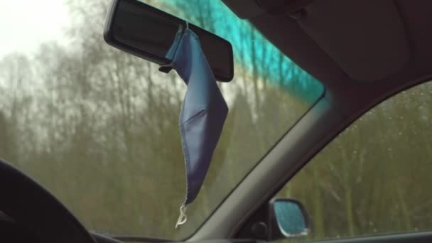 A máscara facial no carro está pendurada no espelho retrovisor. — Vídeo de Stock