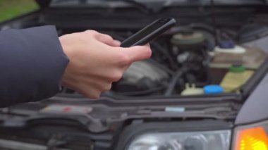 Arabanın arka planında yanıp sönen alarmı olan bir telefon kullanarak yakın plan görüntüsü.