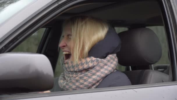 Joven rubia está enojada y gritando mientras está sentada detrás del volante. — Vídeos de Stock