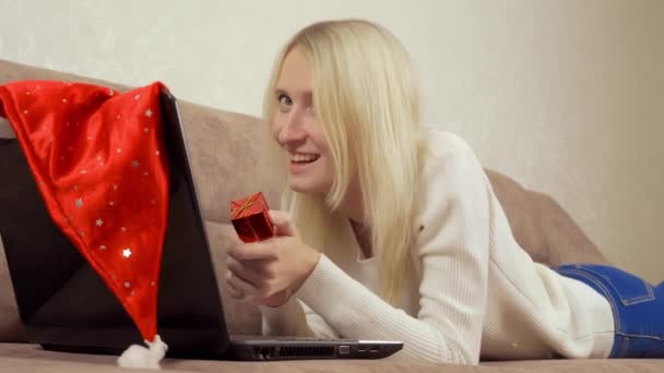 Eine Frau hält ein Geschenk in der Hand und kommuniziert über einen Laptop. Narren — Stockvideo