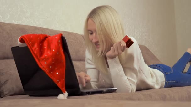 Une femme tient un cadeau et tape sur un ordinateur portable. Acheter sur Internet. — Video