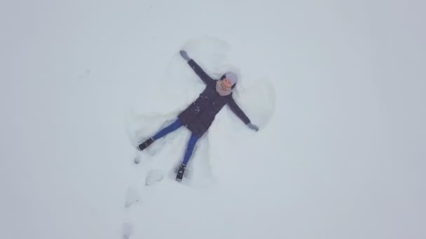 Jeune femme insouciante agitant ses bras et ses jambes dans une dérive de neige. Ange — Video