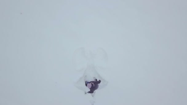 En bekymmerslös ung kvinna som viftar med armar och ben i en snödriva. Ängel — Stockvideo
