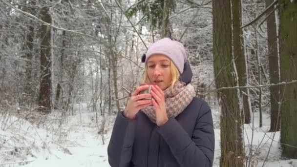 Молодая женщина пьет горячий напиток. Пар из горячего кофе или чая. Зимний лагерь. — стоковое видео