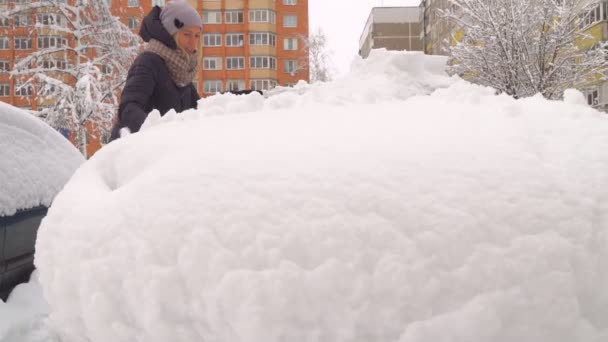 Eine Frau reinigt das Auto mit einer Bürste vom Schnee. — Stockvideo