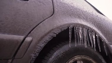 Buzlu bir yağmurdan sonra buzlu bir araba. Aynada ve arabanın kemerlerinde buz saçakları asılı..