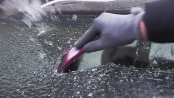 Mujer raspa el hielo del parabrisas de su coche después de un largo estacionamiento. — Vídeos de Stock