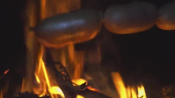Mãos de mulher close-up pelo fogo e salsichas fritas no fogo à noite. — Vídeo de Stock