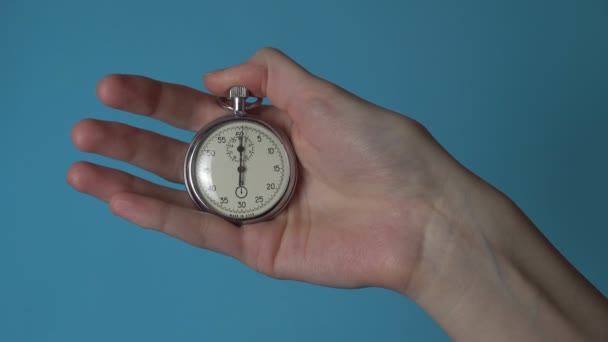 La mano di una donna tiene un cronometro analogico su uno schermo di cromakey blu. — Video Stock