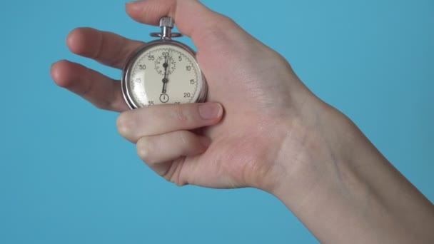 De hand van een vrouw houdt een analoge stopwatch op een blauw chromakey scherm. — Stockvideo