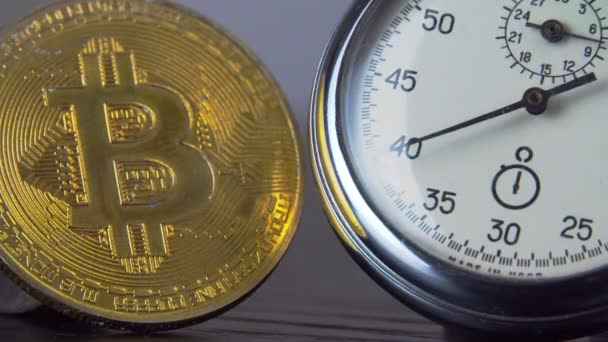 Bitcoin de oro y un cronómetro de metal analógico. Primer plano, macrofotografía. — Vídeos de Stock