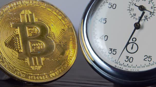 Χρυσό bitcoin και ένα αναλογικό χρονόμετρο. Κοντινό πλάνο, μακροφωτογραφία. — Αρχείο Βίντεο