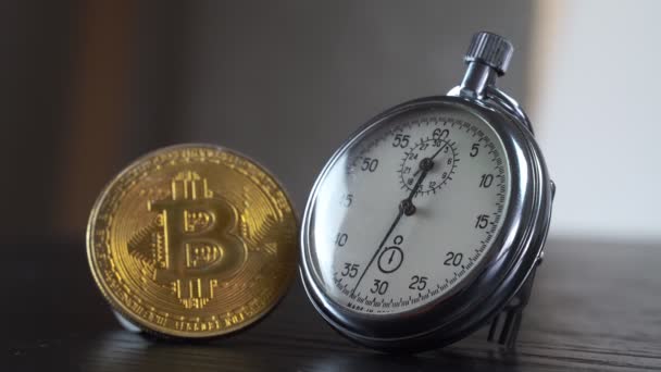 Bitcoin de oro y un cronómetro de metal analógico. Primer plano, macrofotografía. — Vídeo de stock