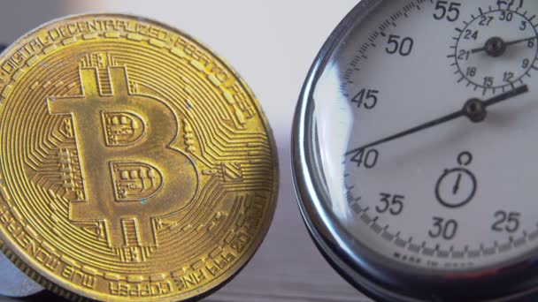 Gouden Bitcoin en een analoge metalen stopwatch. Close-up, macro fotografie. — Stockvideo