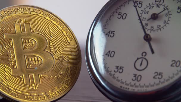 Bitcoin de oro y un cronómetro de metal analógico. Primer plano, macrofotografía. — Vídeos de Stock