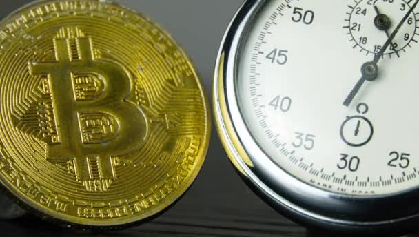 Gouden Bitcoin en een analoge metalen stopwatch. Close-up, macro fotografie. — Stockvideo