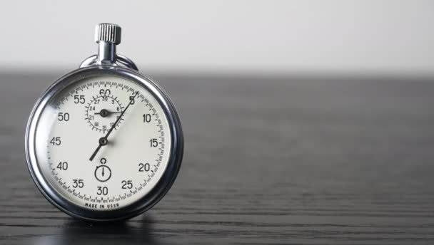 Cronómetro en una mesa de madera oscura. Herramienta de medición de tiempo — Vídeos de Stock