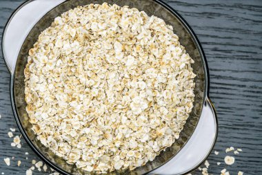 Şeffaf bir kâse içinde kuru yulaf lapası. Arka planda koyu bir yakın plan, üst manzara..