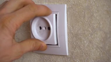 Adamın biri duvara elektrik prizi takıyor. Yakın plan.