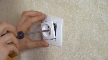 Adamın biri duvara elektrik prizi takıyor. Yakın plan.