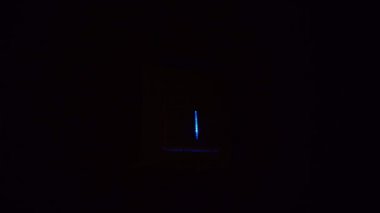 Bir adamın eli duvardaki düğmeyi açıp kapatır ve ışık yanar..