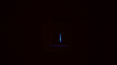 Bir adamın eli duvardaki düğmeyi açıp kapatır ve ışık yanar..