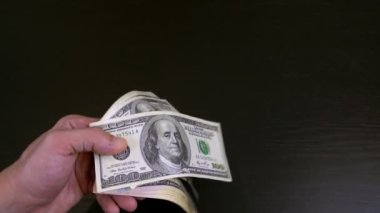 Erkeklerin elleri rastgele titrer ve ellerindeki tomar tomar doları çevirir..