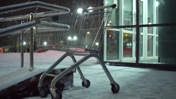 Wózek spożywczy stoi na parkingu supermarketu w nocy w ciężkich opadach śniegu. — Wideo stockowe