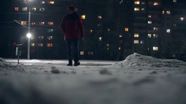 Kamera yerden çekim yapar, adam kışın gece boyunca yürür..