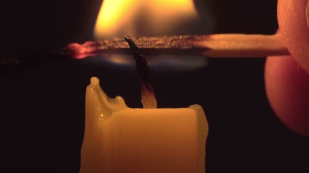 Close-up female hands sets fire a candle by match in darkness. — Stock Video