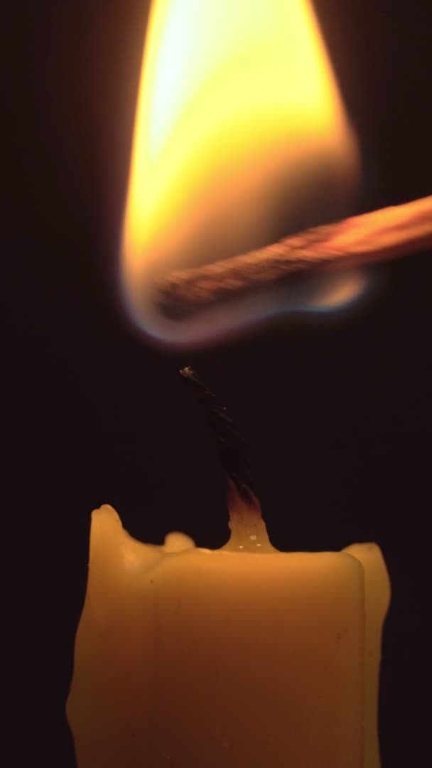 Close-up mãos femininas incendeia uma vela por jogo na escuridão. — Vídeo de Stock