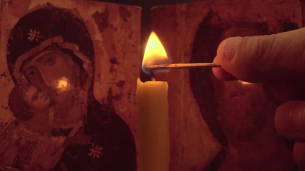 男人的手在一个图标的背景上用火柴点燃教堂的蜡烛 — 图库视频影像