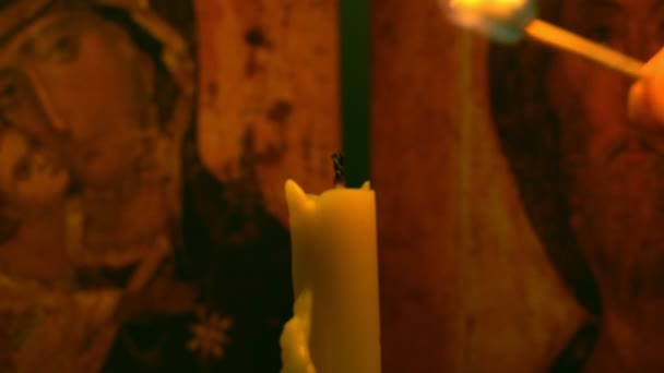 Man's hand lights church candle with match on background of an icon — Stock Video