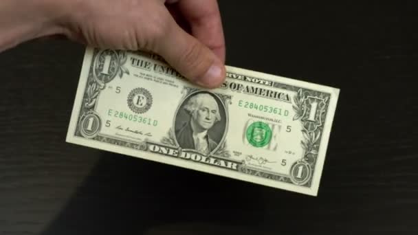 La mano de un hombre sobre un fondo negro sostiene un dólar en su mano, — Vídeo de stock
