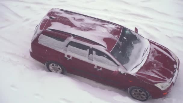 Egy elhagyatott autó az úton télen egy hóesésben. Erős hó, — Stock videók