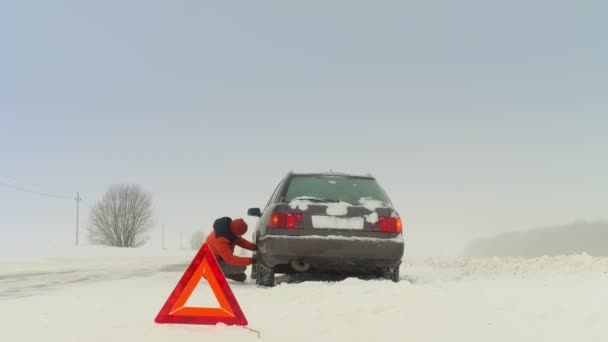 Daño al vehículo en invierno. El hombre sacude la rueda. Explora — Vídeo de stock