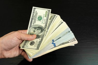 Adamın elinde bir tomar dolar ve siyah bir fana yakın çekim var.