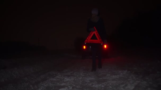 Bir kız, kış gecesi arabasının yanına acil durum levhası asar.. — Stok video