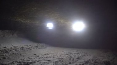 Geceleri şiddetli kar fırtınası sırasında araba kış yolunda park halindedir..